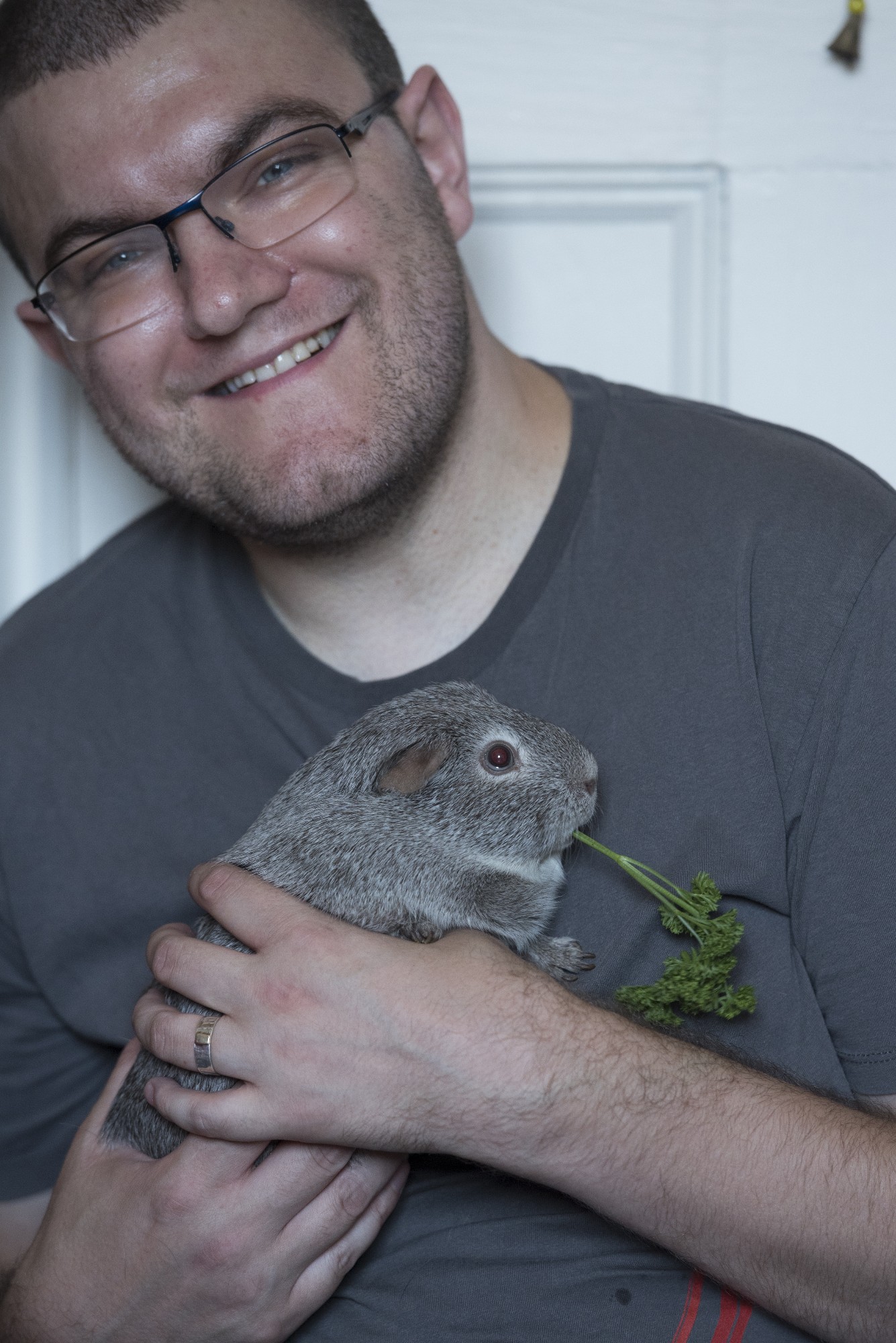 Me, a white mid-30s man with glasses and short brown hair holding Jane the guinea pig, a dear little grey piggy. 