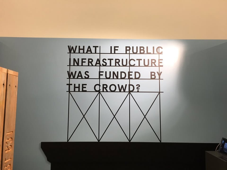 A sign that says "what if public infrastructure was funded by the crowd?"
