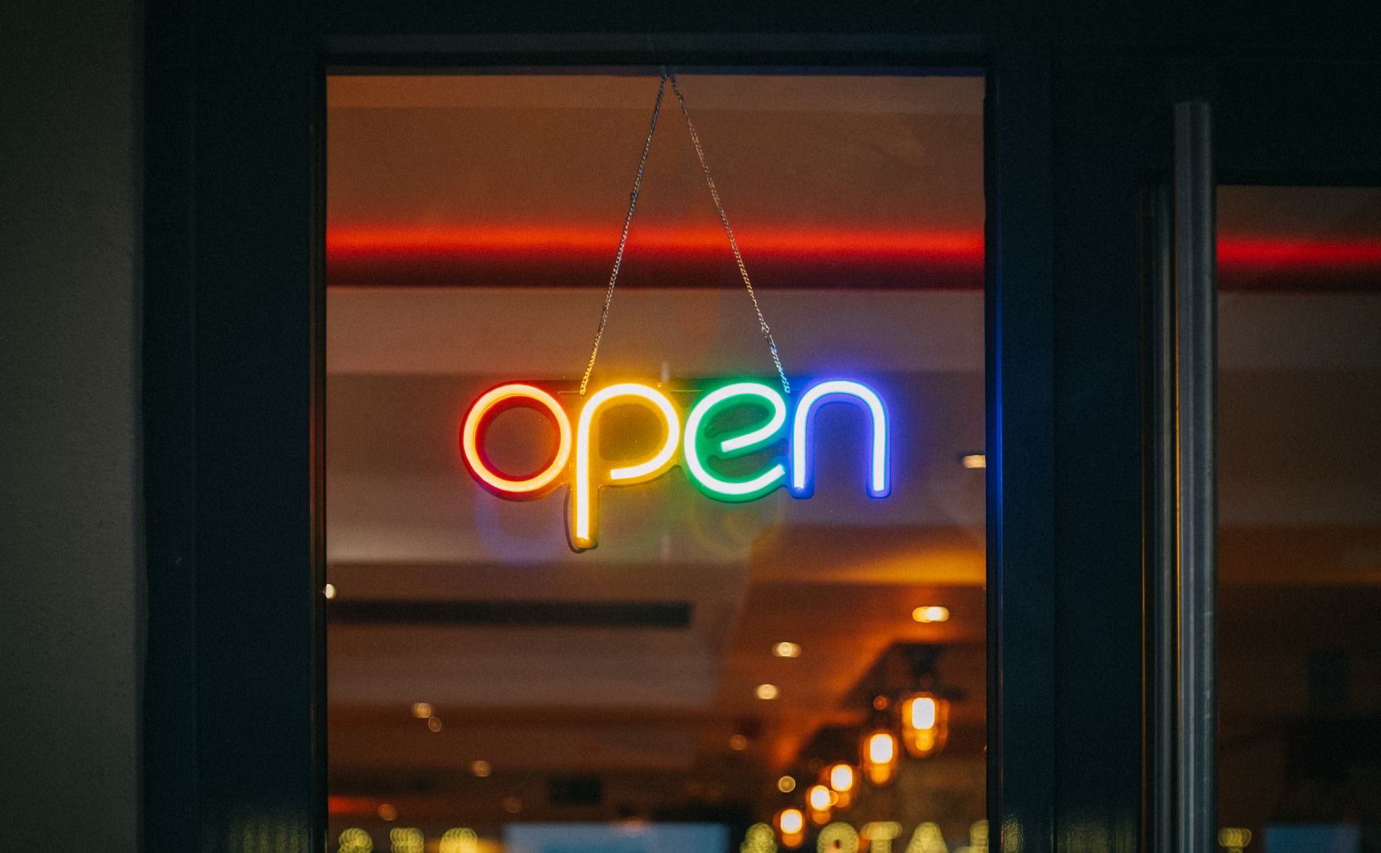 A shop sign in brightly coloured neon letters that says "open"