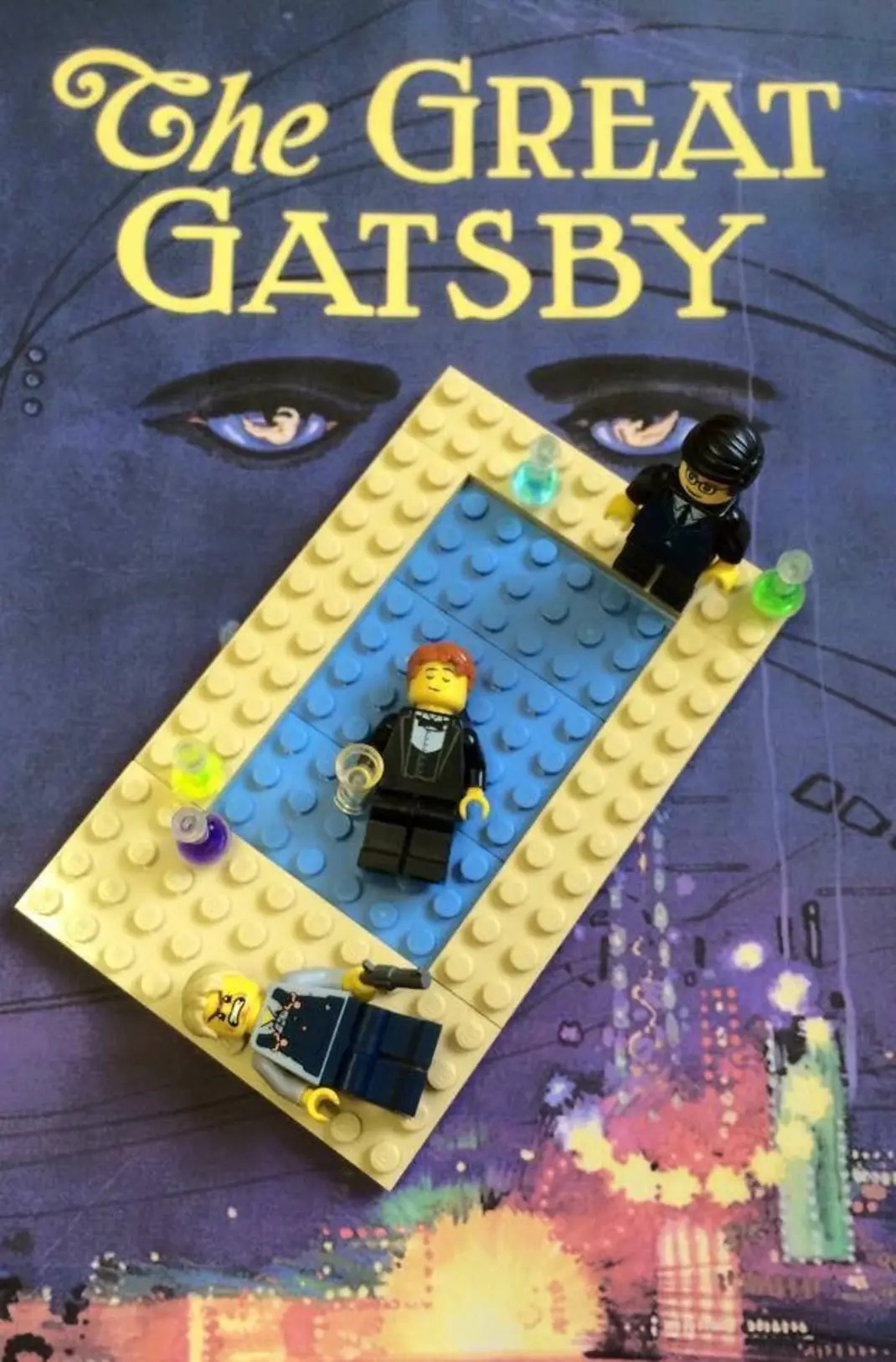 The front cover of The Great Gatsby with a Lego man lying in a swimming pool, with another figure with a gun, and another looking on