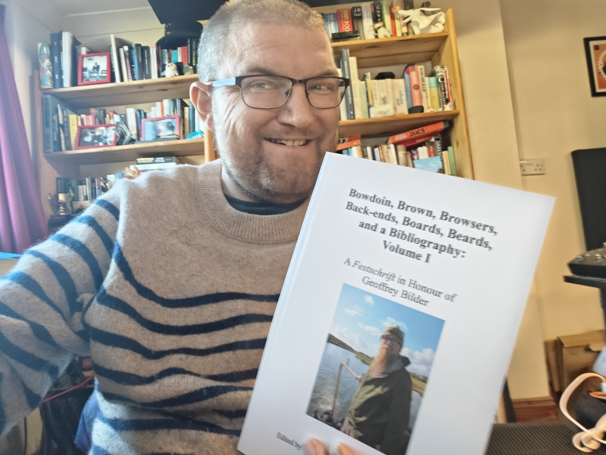 A picture of me holding Geoffrey Bilder's festschrift in a print copy. I have a goofy smile. 