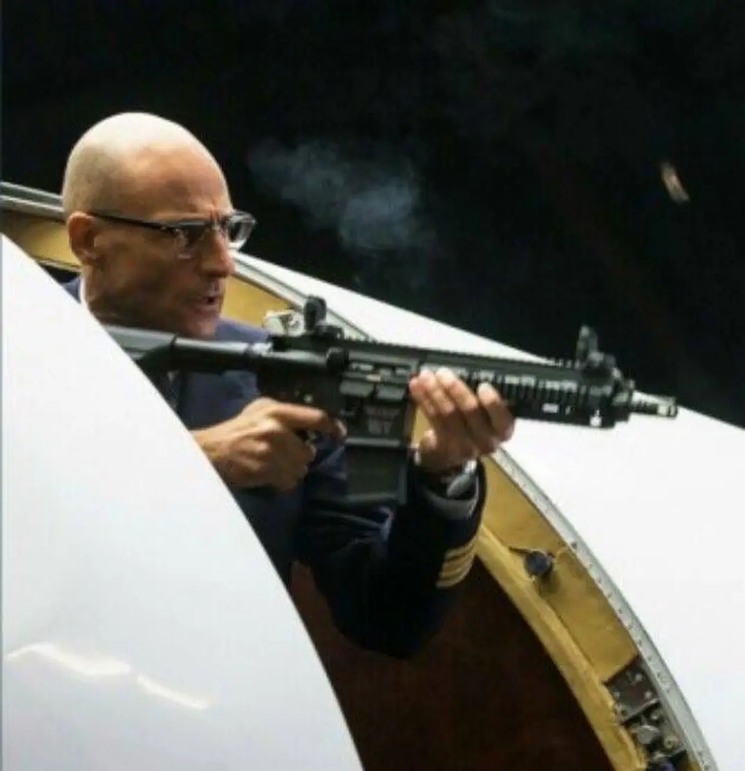 A bald bloke who looks like Foucault with a huge automatic weapon 