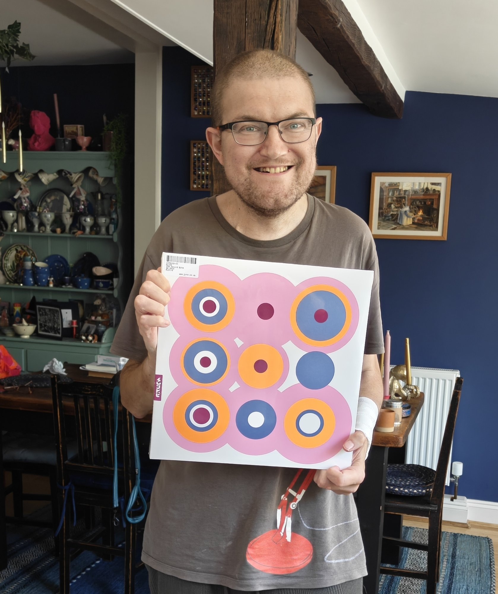 A picture of me holding a vinyl record, which is Fluke - The Second Bite. It is a colourful series of concentric circles, predominantly pink. 