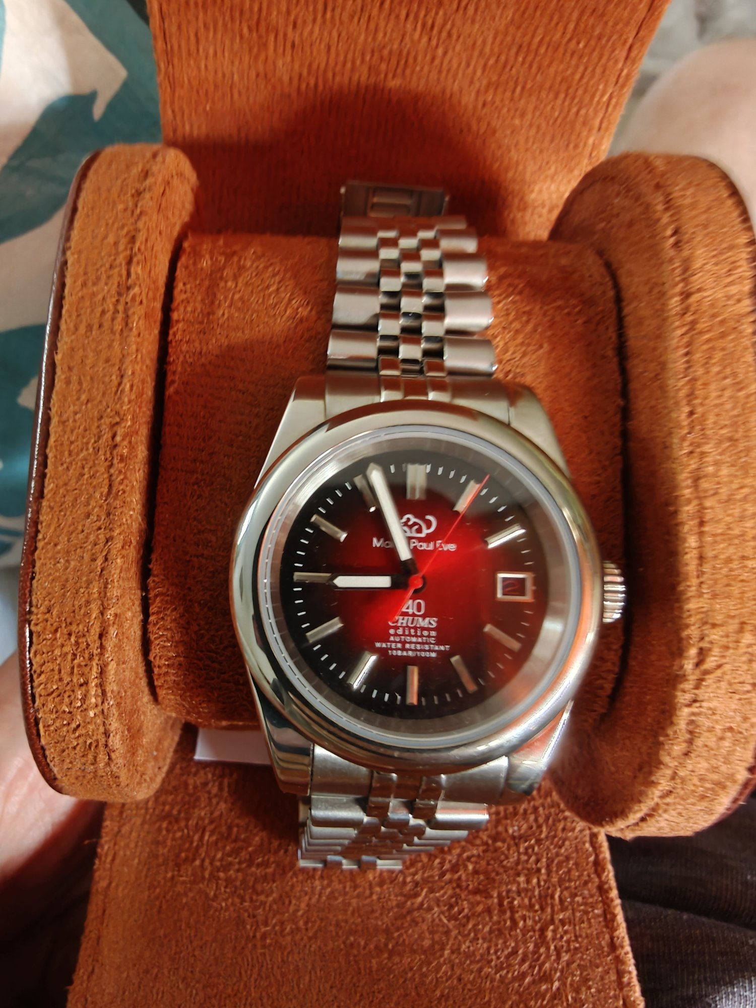 A silver watch with a red interior on the watch face. At the top is a stylised mouse logo and the text Martin Paul Eve. At the bottom is the text 40, Chums Edition. 
