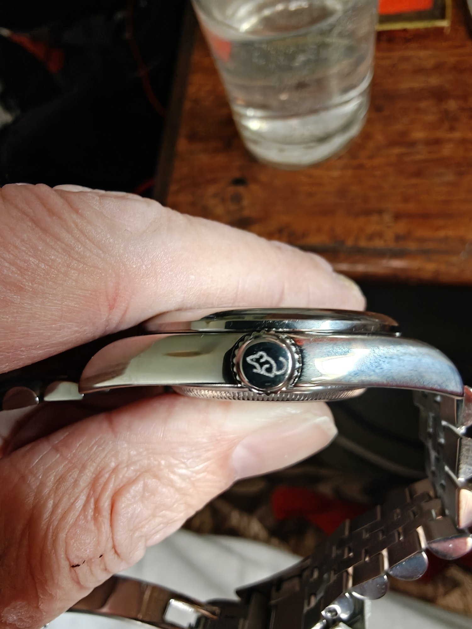 The side of the watch with the winder visible. It has a stylised mouse on it. 
