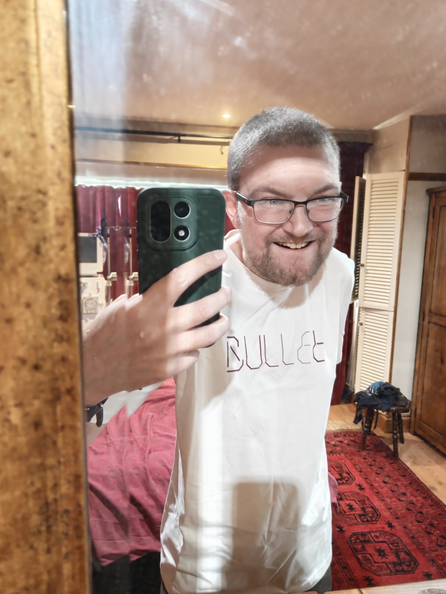 A picture of me, a while middle aged man, wearing a white t shirt that says BULLET in a stylised fashion. 